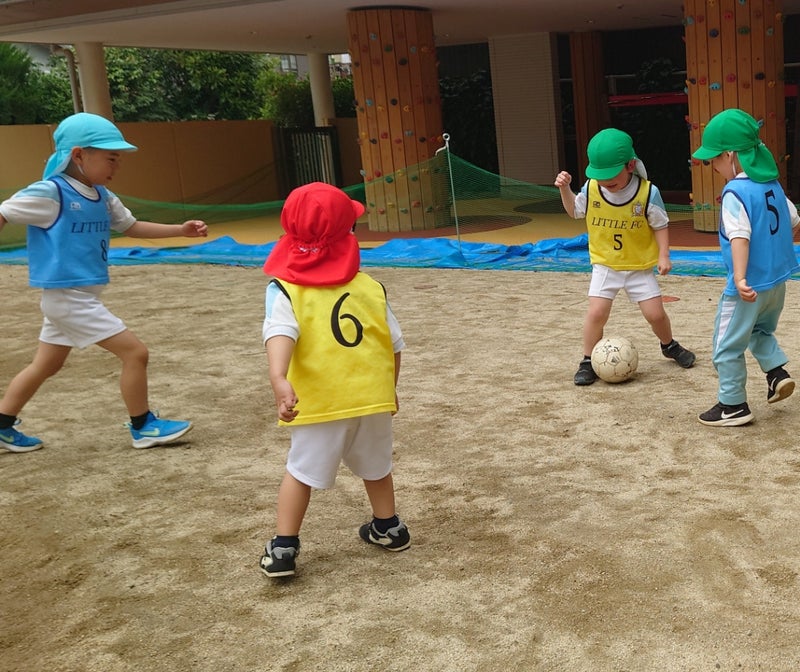 Toddlers in blue and yellow practice bibs playing with a soccer ball